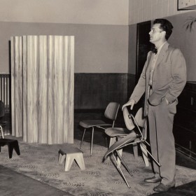 Charles Eames with molded plywood chairs and screenFEATURED